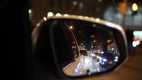Car-driving-through-urban-city,-looking-through-rear-view-mirror