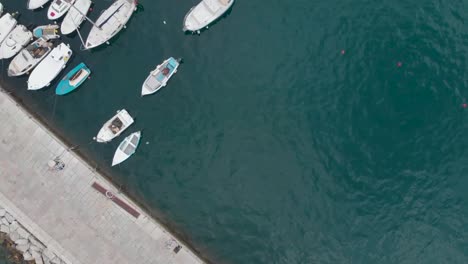 Top-down-drone-shot-a-stone-pier-and-anchored-boats