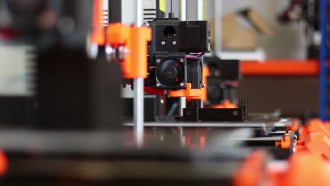 A-collection-of-three-3D-Printers-shows-them-all-printing,-the-camera-racks-focus-from-the-middle-printer-to-the-closest-one