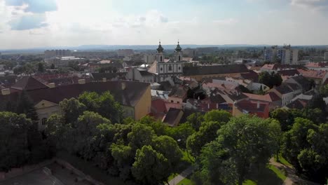 Turning-and-ascending-drone-shot-over-a-city-with-churches-and-lush-green-trees