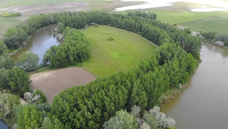 Aerial-drone-shot-of-a-backwater-river-bend-with-a-green-field-in-the-middle