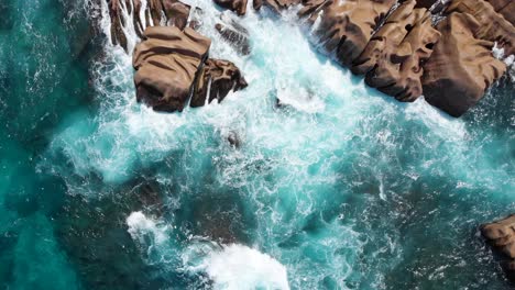 Zoom-out-aerial-view-of-waves-breaking-on-the-granite-rocks-of-Anse-Marron-on-La-Digues-south-tip