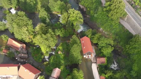 Top-down-view-of-a-small-green-village-dotted-with-waterfalls-and-rivers