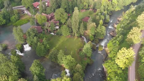 Pull-back-drone-shot-of-a-small-milling-village-surrounded-by-waterfalls