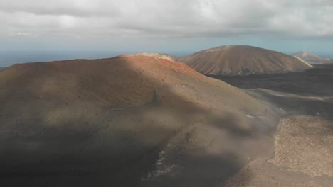 Ascending-drone-shot-over-a-red-volcano-revealing-the-ocean