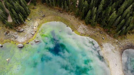 Drone-Volando-Sobre-Un-Hermoso-Lago-Glaciar-Reflectante-Rodeado-De-árboles-En-Dolomitas-En-Italia