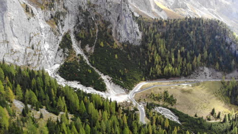 Drone-Inclinándose-Hacia-Arriba-De-Los-árboles-Para-Revelar-Una-Montaña-Gigante-En-Los-Dolomitas-Italianos