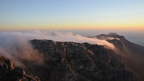 Clouds-over-Table-Mountain,-known-as-the-table-cloth,-during-sunset-over-the-twelve-apostles-side