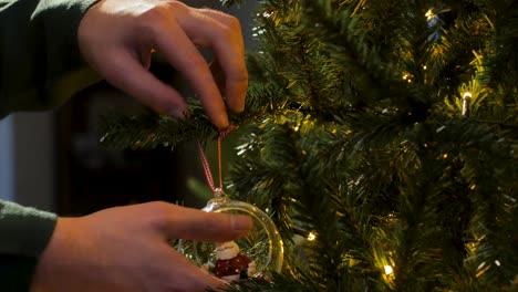 Mann-Mit-Grünem-Weihnachtspullover,-Der-Eine-Klare-Verzierung-Mit-Weihnachtsmann-In-Einer-Kiefer-Oder-Einem-Weihnachtsbaum-Hängt,-Nahaufnahme,-Seitenansicht