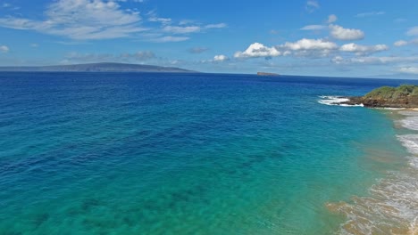 Panning-Luftaufnahme-über-Klarem-Blauem-Wasser-In-Hawaii-Mit-Land-Im-Hintergrund