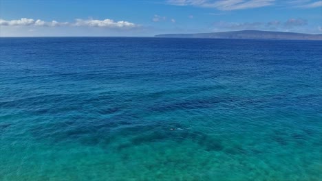 Panning-aerial-shot-of-a-snorkeler-in-Maui-Hawaii-in-beautiful-blue-water