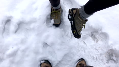 Man-and-woman-wearing-snow-cleats-during-a-snowstorm