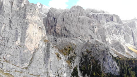 Drone-flying-away-from-gigantic-mountain-face-in-Italian-Dolomite-Alps