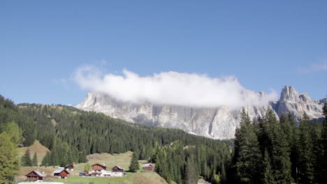 Dolomite-mountain-with-clouds-time-lapse-with-rustic-buildings-near-by