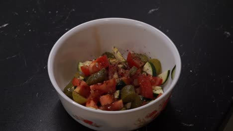 Healthy-fresh-salad-bowl-with-a-lot-of-chopped-ingredients-being-flavoured,-vegetables-added-and-mixed-with-spoons