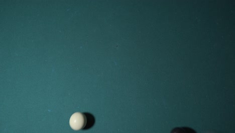 Overhead-view-of-8-ball-being-hit-out-of-frame-by-white-ball-in-billiards-game