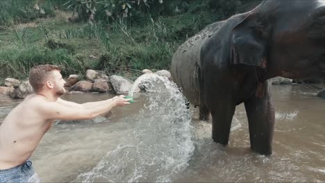 Männlicher-Tourist,-Der-Großen-Asiatischen-Elefanten-In-Einem-Fluss-In-Thailand-Wäscht