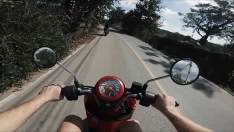 POV-shot-of-a-man-driving-a-moped-down-a-country-road-in-Thailand