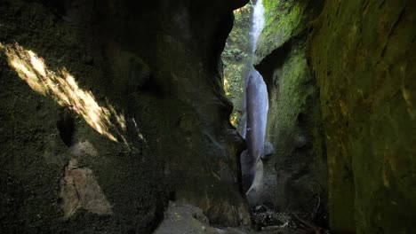 Wide,-slow-motion-shot-of-a-hidden-waterfall-in-a-canyon