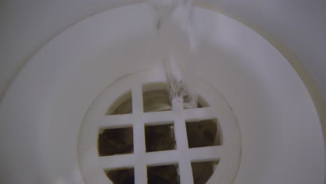 Water-vortex-shot-underwater-extreme-macro-close-up-of-a-bathtub-plug-hole-as-bath-water-empties-with-a-jumpy-thick-swirling-vortex-above-the-hole