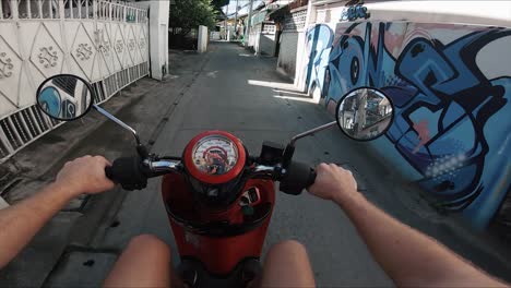 Tiro-Pov-De-Un-Hombre-Conduciendo-Un-Ciclomotor-A-Través-De-Una-Calle-Callejón-En-Chiang-Mai,-Tailandia