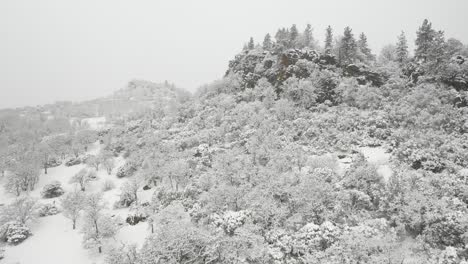 Aerial-view-of-drone-approaching-a-rocky-outcropping-during-a-winter-snow-storm