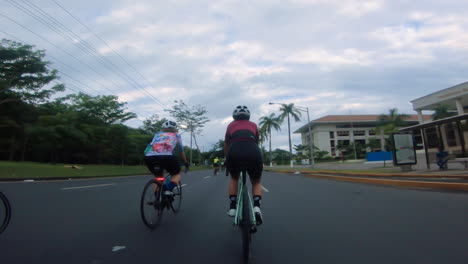 Two-cyclists-riding-on-a-long-stretch-of-road-and-past-palm-trees