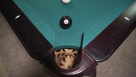 Player-sinking-black-8-ball-into-corner-pocket-to-win-game-of-billiards
