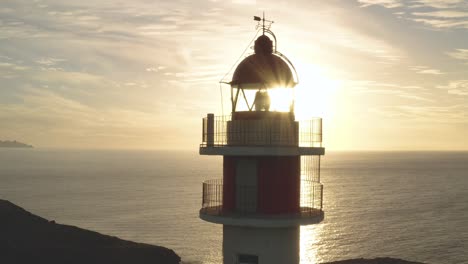 Close-drone-shot-of-a-lighthouse-with-sun-and-ocean-in-the-background-at-golden-hour