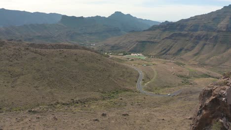 Drohnenaufnahme-Der-Straße-Im-Hintergrund-Mit-Einem-Großen-Felsen,-Gran-Canaria