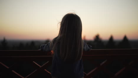 Silhouette-of-little-girl-standing-on-watchtower-at-sunset