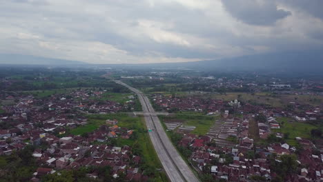 Aerial-high-drone-flight-over-evening-road-and-houses-in-village-in-Java-in-Indonesia