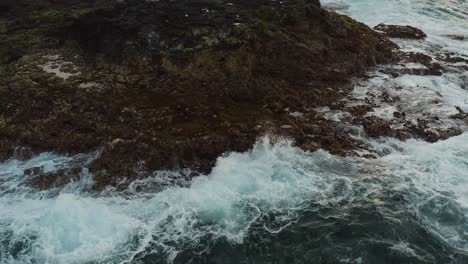 Close-drone-shot-of-waves-splashing-on-the-coast-of-an-ocean