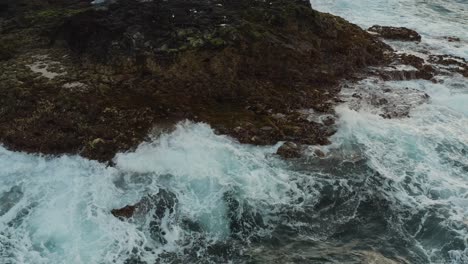 Close-drone-shot-of-waves-splashing-on-the-coast-of-an-ocean
