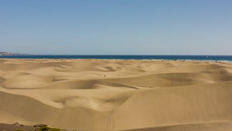 Drohnenaufnahme-Von-Wüste-Und-Dünen-Mit-Strand-Und-Meer,-Dunas-De-Maspalomas,-Gran-Canaria