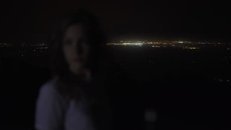 Woman-on-high-mountain-watching-lights-of-towns-at-night-in-Mallorca,-Spain