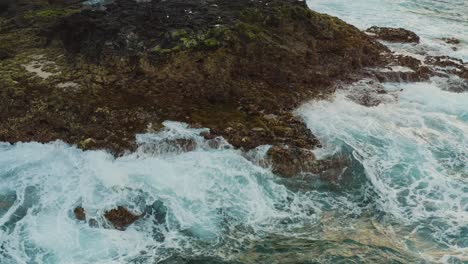 Drone-shot-of-waves-bounce-on-a-rock-at-the-beach