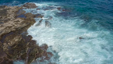 Drone-shot-of-waves-bounce-on-rocks-at-the-beach