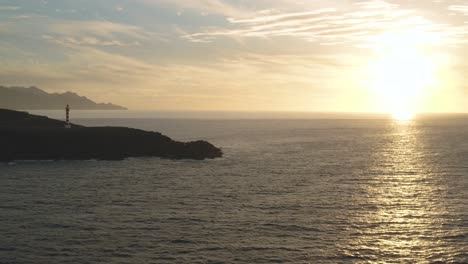 Panoramadrohnenaufnahme-Eines-Leuchtturms-Zur-Goldenen-Stunde-Mit-Meer-Und-Sonne