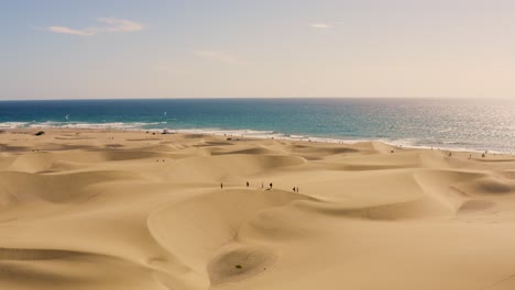 Drone-shot-of-dunes-and-desert-with-beach-in-the-background,-dunas-de-maspalomas,-gran-canaria