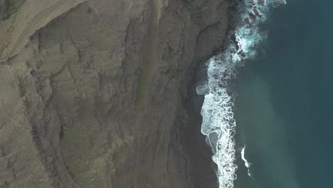 Drone-top-down-shot-of-waves-bounce-on-rocks-at-the-coast