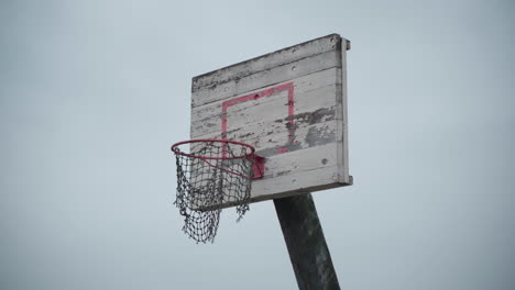 Alter-Basketballkorb-Mit-Zerrissenem-Netz,-Das-Im-Wind-Hängt-Und-Farbe-Abblättert