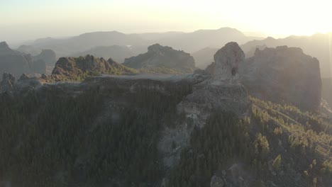 Schöne-Drohne,-Die-Zur-Goldenen-Stunde-Mit-Linseneffekt-Eines-Bergpanoramas-Mit-Wald-Von-Roque-Nublo,-Gran-Canaria,-Aufgenommen-Wurde