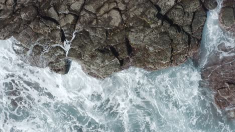 Top-shot-of-a-drone-waves-splashing-on-the-coast-of-an-ocean