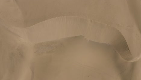 Drone-top-shot-of-dunes-in-a-desert-with-windy-sand