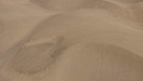 Drone-shot-of-dunes-in-a-desert-with-windy-sand