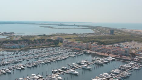 Cinematic-drone---aerial-tracking-panorama-shot-of-a-marina---port-with-sailing-boats-on-a-sunny-day-with-the-north-sea-in-the-background,-30p