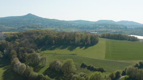 Drone---Aerial-panorama-fly-over-shot-of-a-meadow-with-grass-and-bushes-and-the-Siebengebirge---seven-mountains-in-the-background-30p
