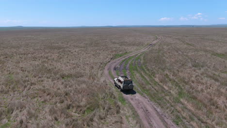 Drohnenaufnahme-Eines-Geländewagens-Fährt-Durch-Grasland-In-Der-Serengeti