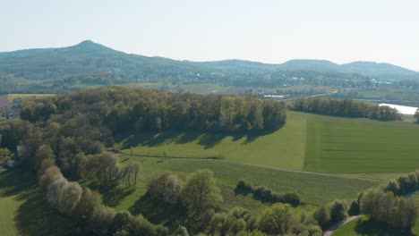Drone---Aerial-panorama-fly-over-shot-of-a-meadow-with-grass-and-bushes-and-the-Siebengebirge---seven-mountains-in-the-background-25p
